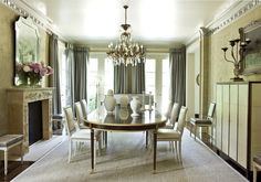 an elegant dining room with chandelier and table surrounded by chairs in front of a fireplace