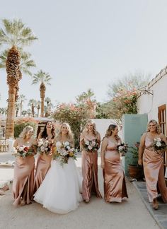 a group of women standing next to each other in front of a building with palm trees