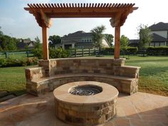 an outdoor fire pit in the middle of a yard with a pergolated roof