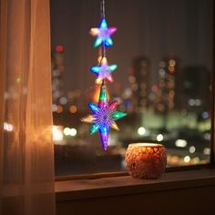 a window sill with three lights hanging from it's sides and in front of a cityscape