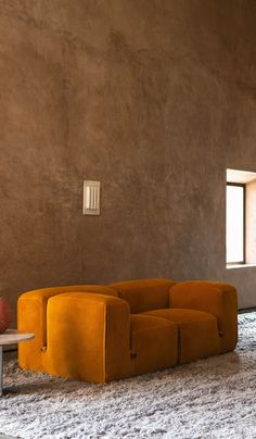 an orange couch sitting in the middle of a living room next to a white table