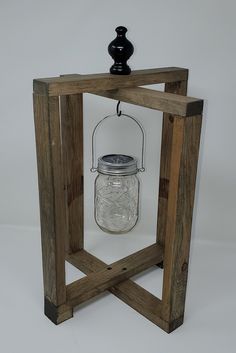 a mason jar in a wooden frame with a black candle holder on the top and bottom