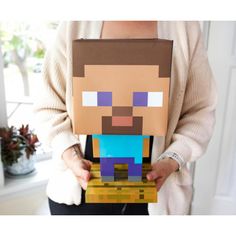 a person holding a paper cut out of a minecraft man in front of a window