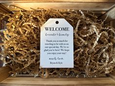 a wooden box filled with lots of wood shavings and a welcome tag attached to it