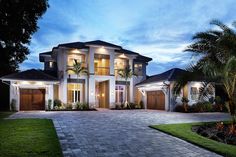 a large house with two car garages and palm trees in the front yard at night