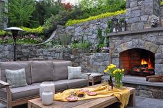 an outdoor living area with couches, table and fire place in the middle of it