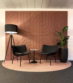 two black chairs sitting next to each other in front of a wall with a plant