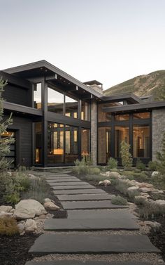 a modern house in the mountains with stone walkway