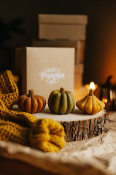 three small pumpkins sitting on top of a table next to a box and scarf