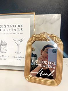 there is a gold frame with a picture on it next to a book and a drink