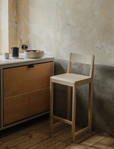 a white chair sitting next to a wooden dresser in a room with no one on it