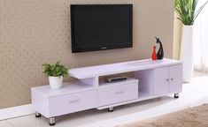 a white entertainment center with drawers and a flat screen tv mounted on the wall