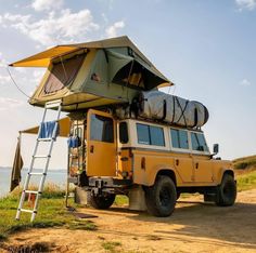 an off road vehicle with a tent on the roof and ladder up to it's top