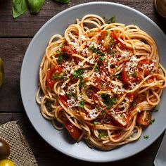 a plate of spaghetti with tomato sauce, parmesan cheese and basil on top