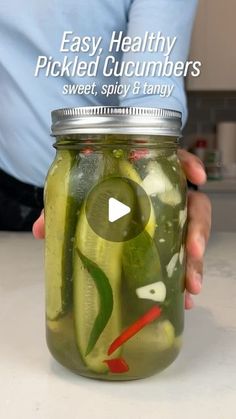 a person holding a jar filled with pickles