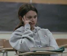 a woman sitting at a desk talking on her cell phone while holding a book in front of her face