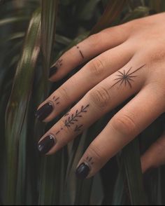 a woman's hand with tattoos on it and an arrow tattoo on the middle finger