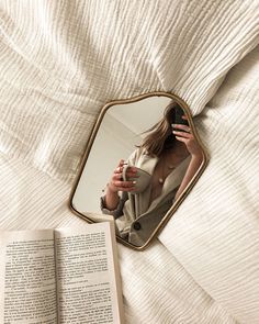 a woman is taking a selfie in the mirror with her cell phone and an open book