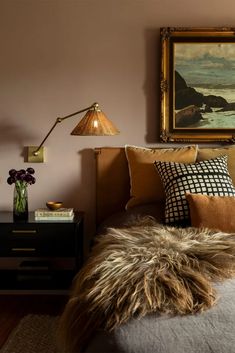 a bed room with a neatly made bed and a painting on the wall above it