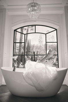 a woman is laying in a bathtub with her feet up on the window sill