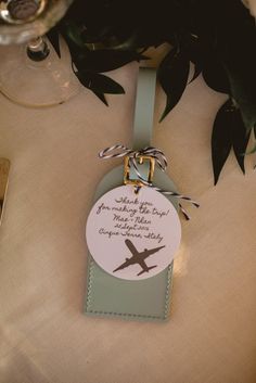 an airplane luggage tag is attached to a table with flowers and wine glasses in the background