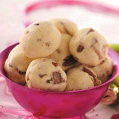 a pink bowl filled with cookies on top of a table