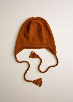 a brown knitted hat with tassels on it