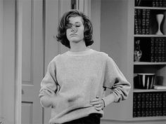 a woman standing in front of a bookshelf with her hands on her hips