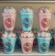 there are many ice creams in plastic cups on the shelf with unicorn candies