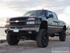 a large black truck parked next to the water