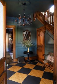 a room with a checkered floor, chandelier and table in it's center