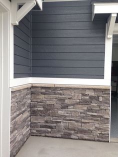 the corner of a house with a stone wall and white trim on the front door