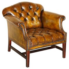 a brown leather chair with wooden legs and nail polishing on the armrests