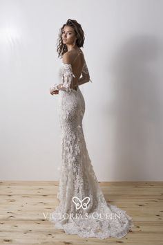 a woman in a white wedding dress standing on a wooden floor with her back to the camera