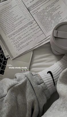 a person's feet on top of a bed next to papers and a laptop