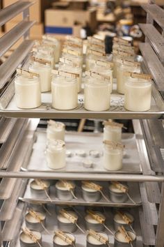 several trays filled with cupcakes on top of a metal shelf in a bakery