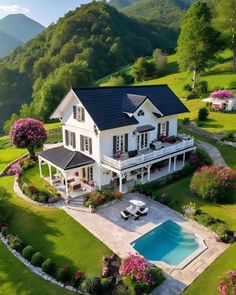 an aerial view of a large house with a pool in the front yard and lush green hills behind it