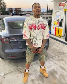 a man standing in front of a car at a gas station with his mouth open