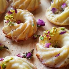 some doughnuts with icing and sprinkles on a cutting board