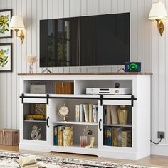 a living room with a large tv on top of a white entertainment center filled with books