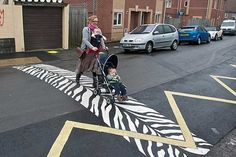 a woman pushing a stroller with a child in it on a zebra painted street