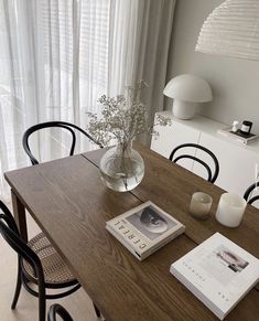 a wooden table topped with a glass vase filled with flowers and two books on top of it