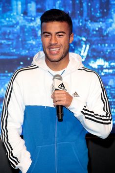 a man holding a microphone in front of a screen with the words adidas on it