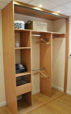 a closet with wooden shelves and clothes hanging on the doors, in front of a window