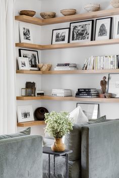 a living room filled with furniture and lots of books on the shelf above it is a vase full of flowers