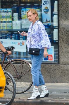 a woman standing next to a bike on the street while looking at her cell phone