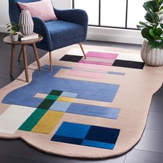 a blue chair sitting on top of a wooden floor next to a rug covered in geometric shapes