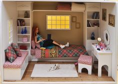 a dollhouse bedroom with a woman sitting on the bed and working on her laptop