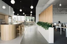 the interior of an office with people working on their laptops and eating at tables