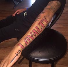 a man sitting on top of a chair with his arm covered in tattoos and writing